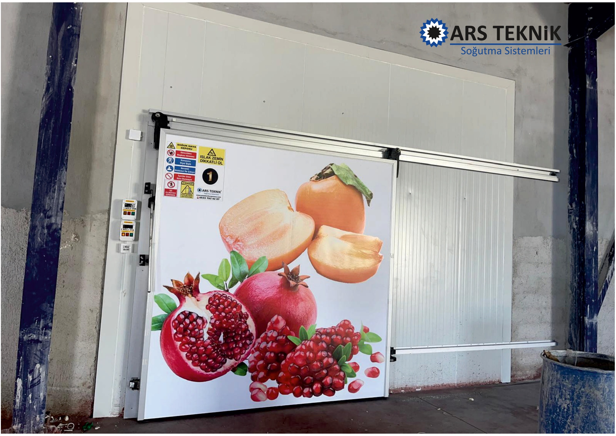 A sliding door on an overhead track, set in a white insulated panel wall.