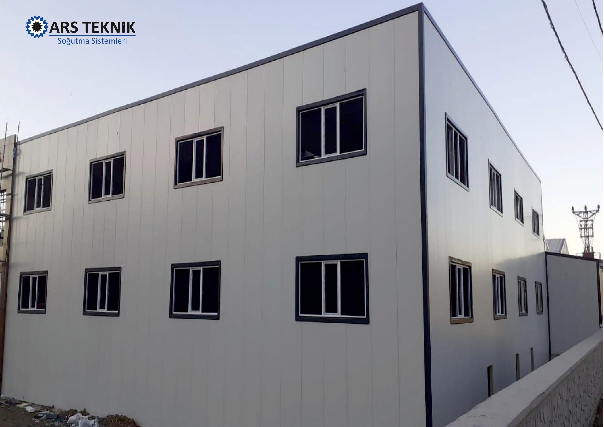 A light-grey panel-clad building exterior with rows of windows.