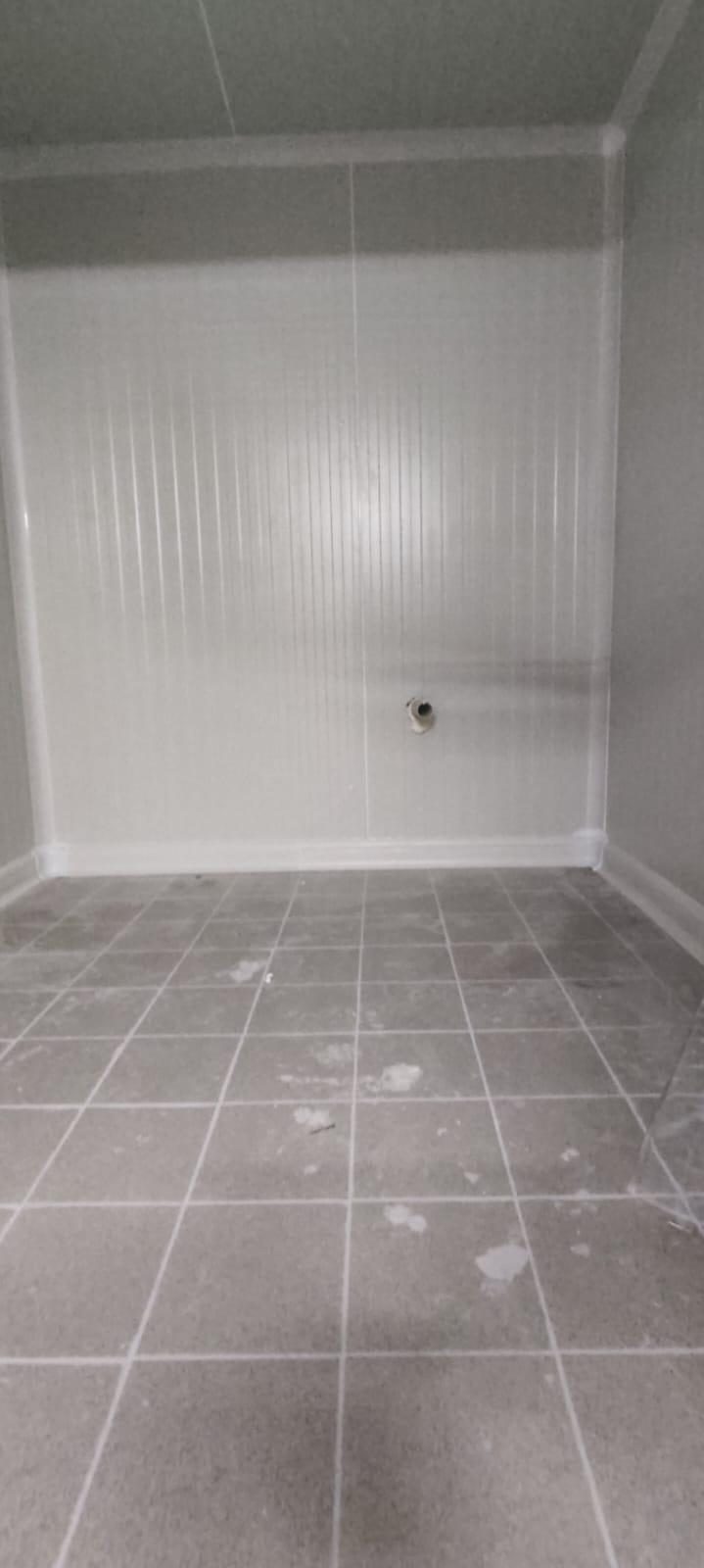 A small room lined with panels and a tiled floor. Panel type and temperature are not stated.