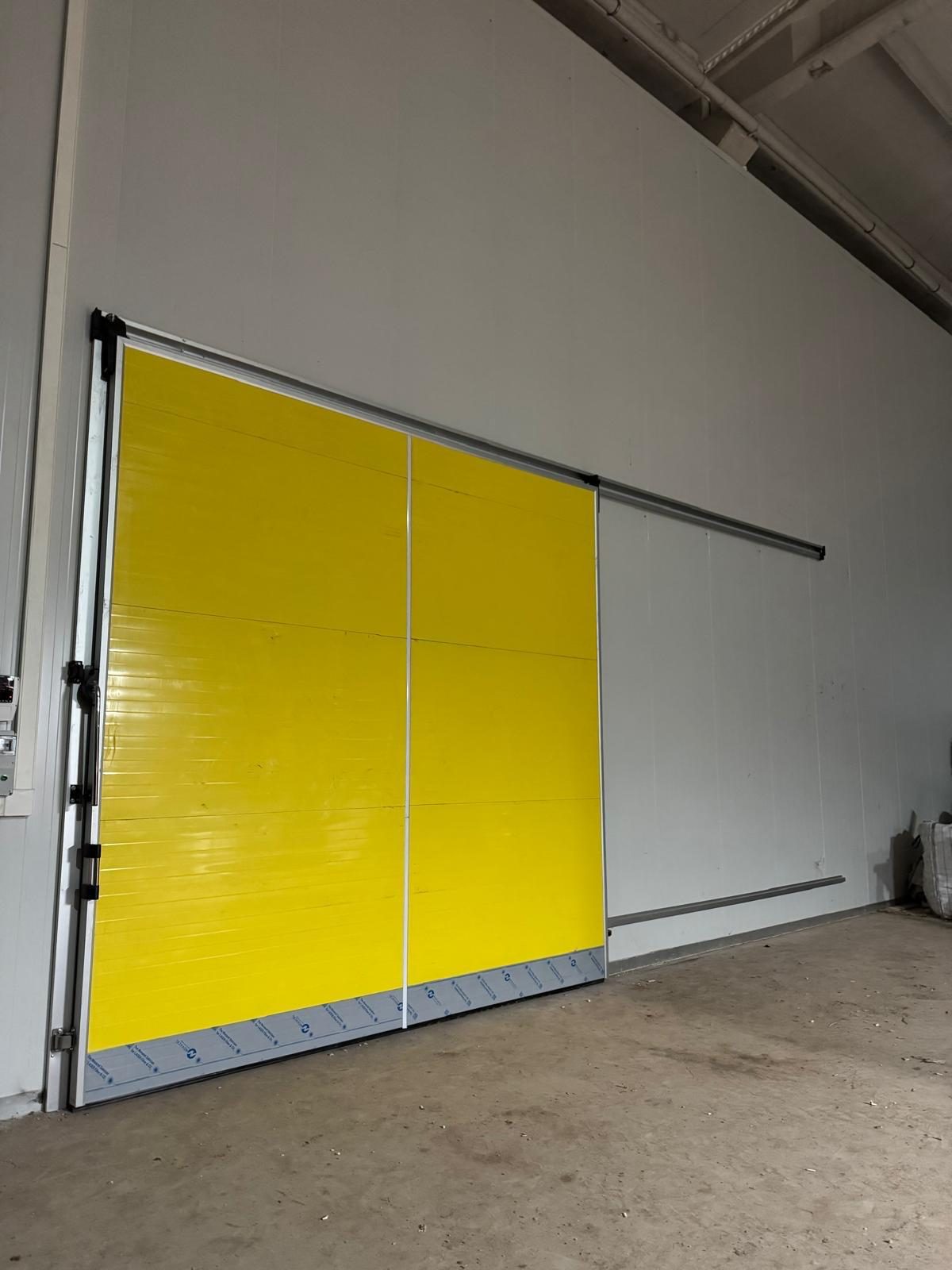 A yellow sliding door on an overhead track. It is not matched to the printed size chart.